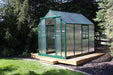 Corner view of Grandio Element 6x8 greenhouse featuring the durable structure and easy-access sliding door, set against natural foliage.