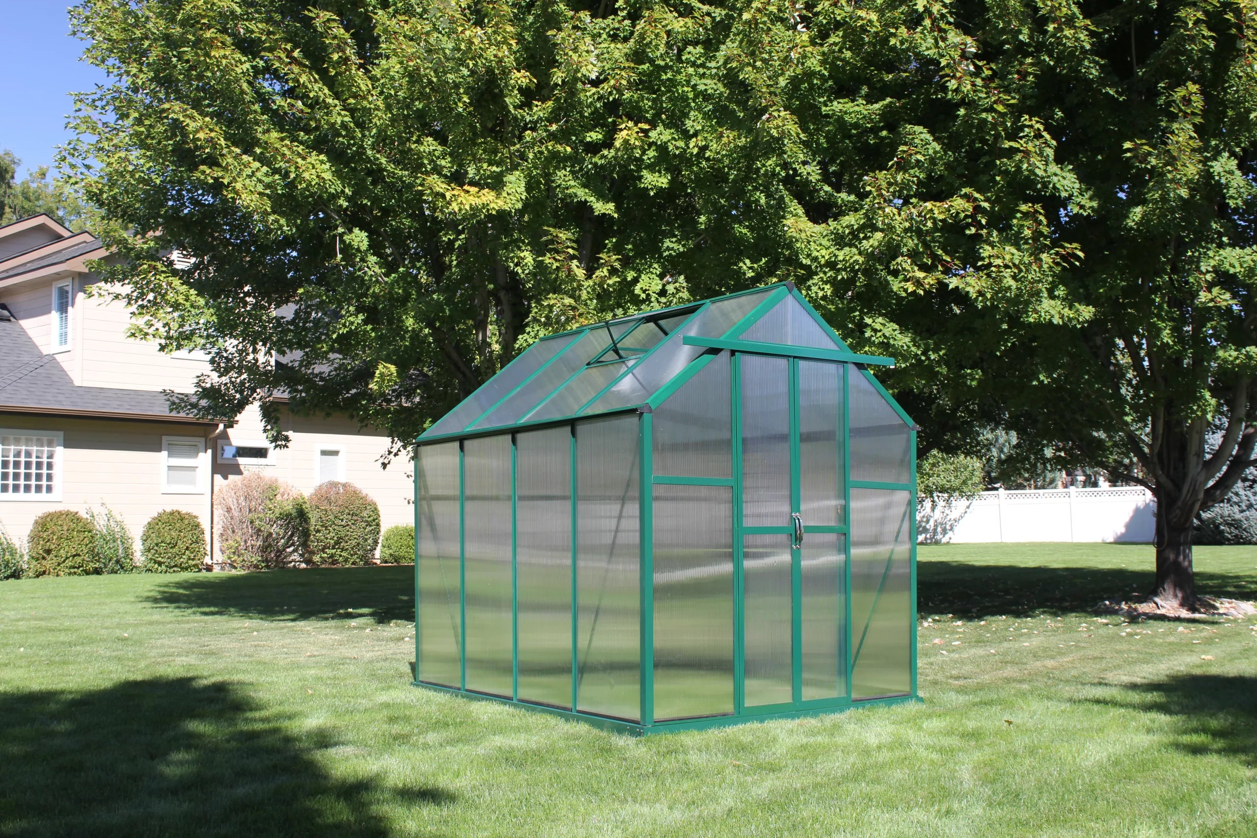 Grandio Element 6x8 greenhouse positioned on lush grass, illustrating the compact design and efficient use of space for gardening.