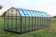 Rear view of a spacious Grandio Elite 8x24 greenhouse in a natural setting with durable construction.