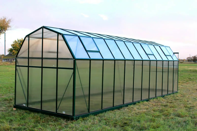 Rear view of a spacious Grandio Elite 8x24 greenhouse in a natural setting with durable construction.