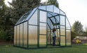 Gardener inside a large Grandio greenhouse assessing plant growth, surrounded by lush greenery